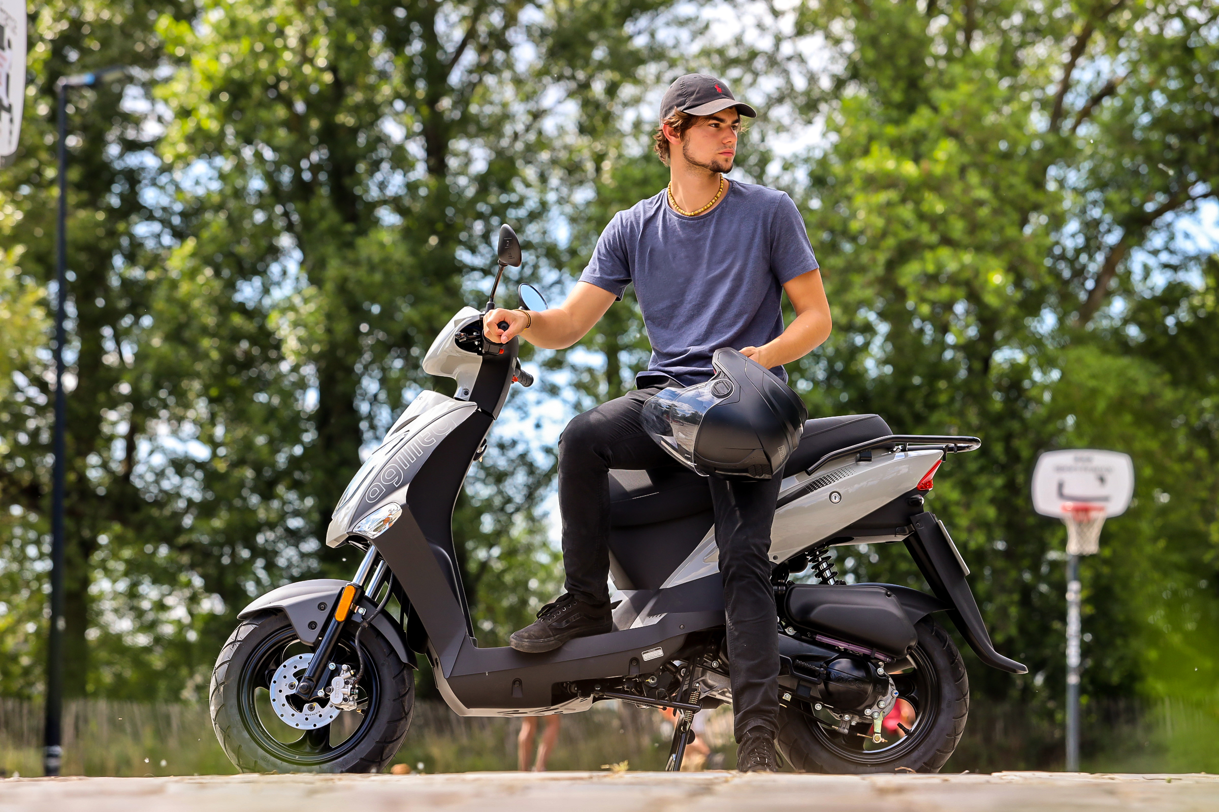 Kymco Agility 50 2024 : profil gauche statique avec jeune homme