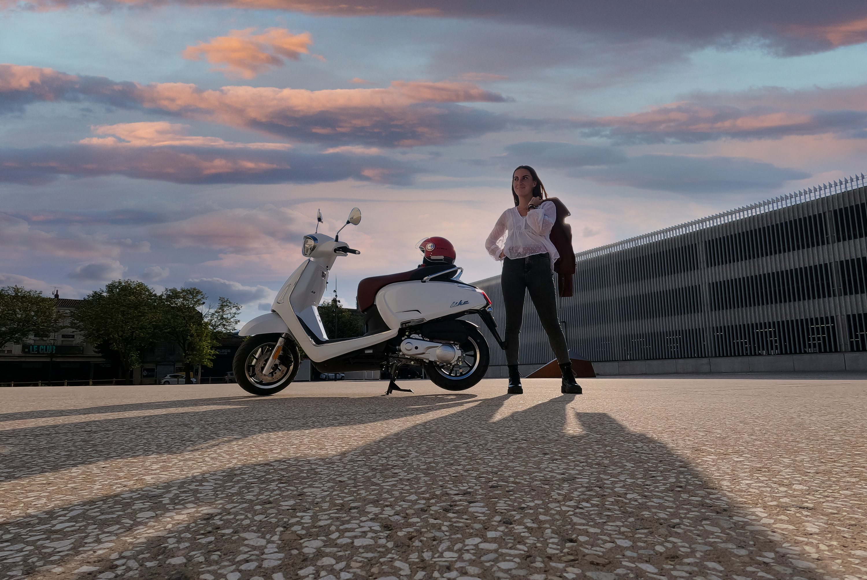 Kymco Like 50 2024 : profil gauche statique avec jeune femme et coucher de soleil