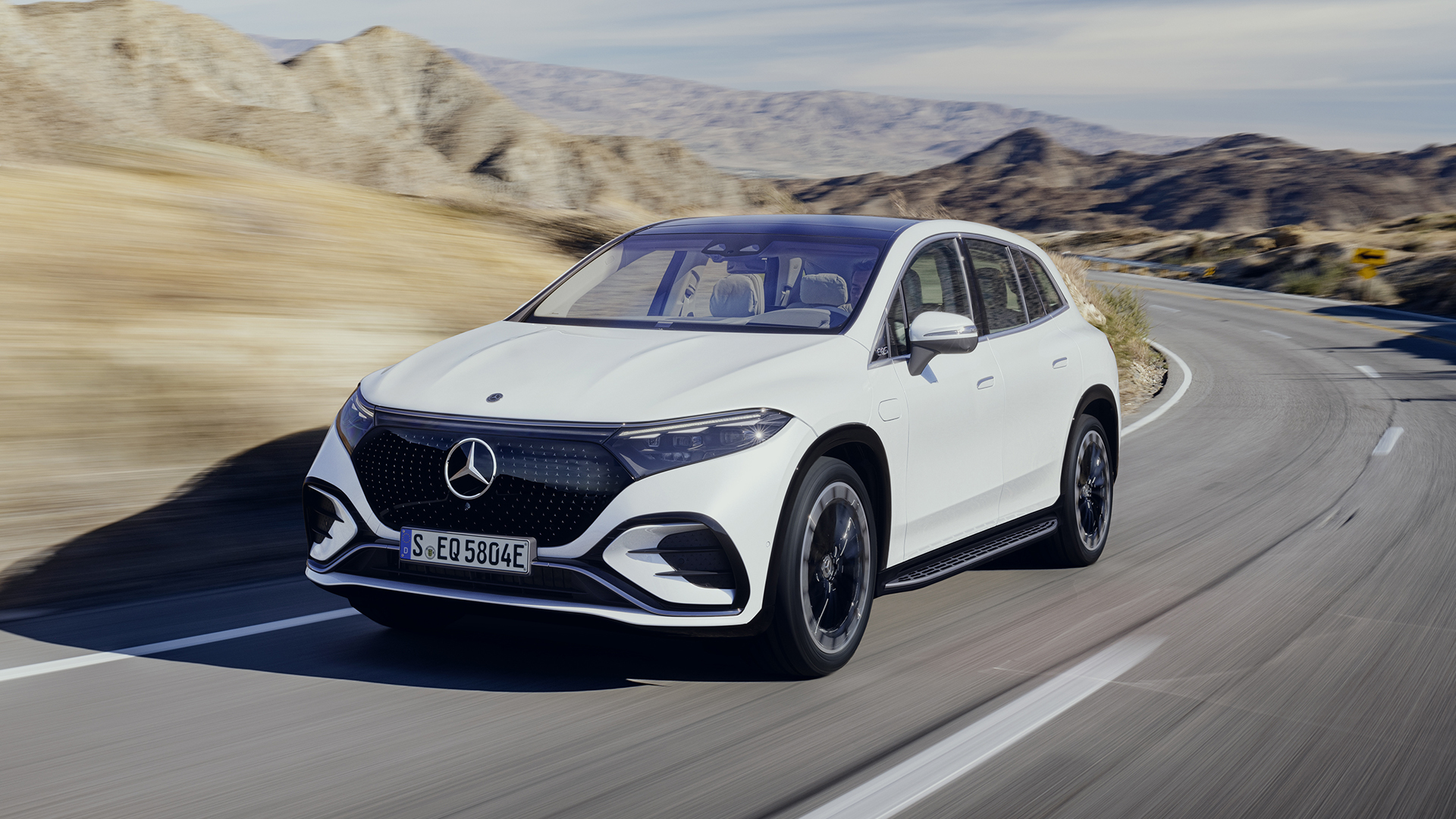 EQS SUV de Mercedes-EQ : Trois quart avant gauche en couleur blanche sur la route en roulant