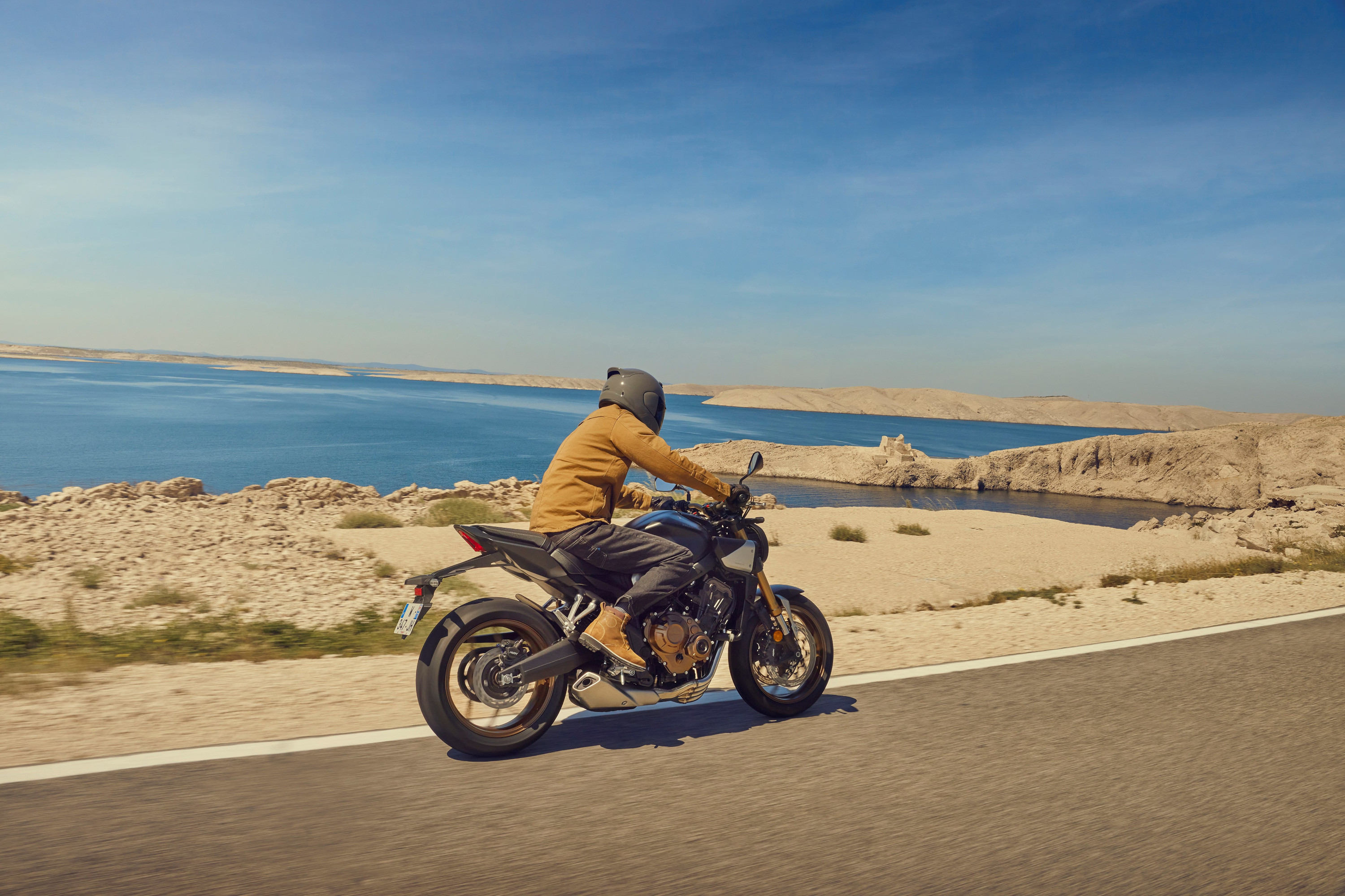 Honda CB650R 2024 : trois quarts arrière droit sur route en bord de mer