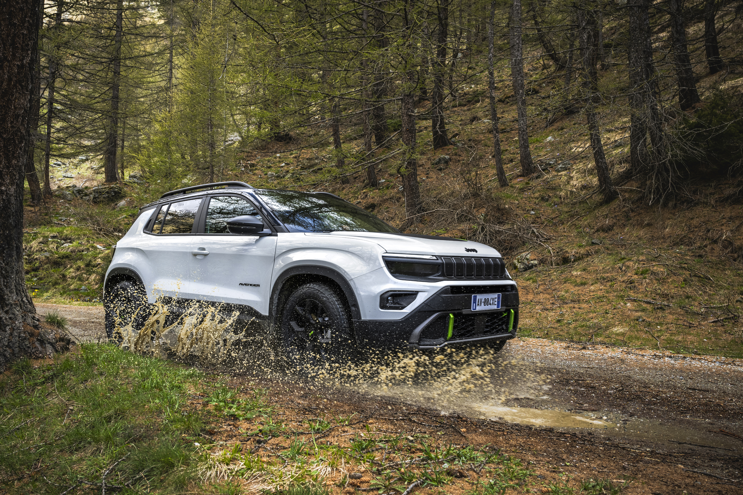 Jeep Avenger 4xe 2024 : trois quarts avant droit traverse une flaque sur une chemin en forêt