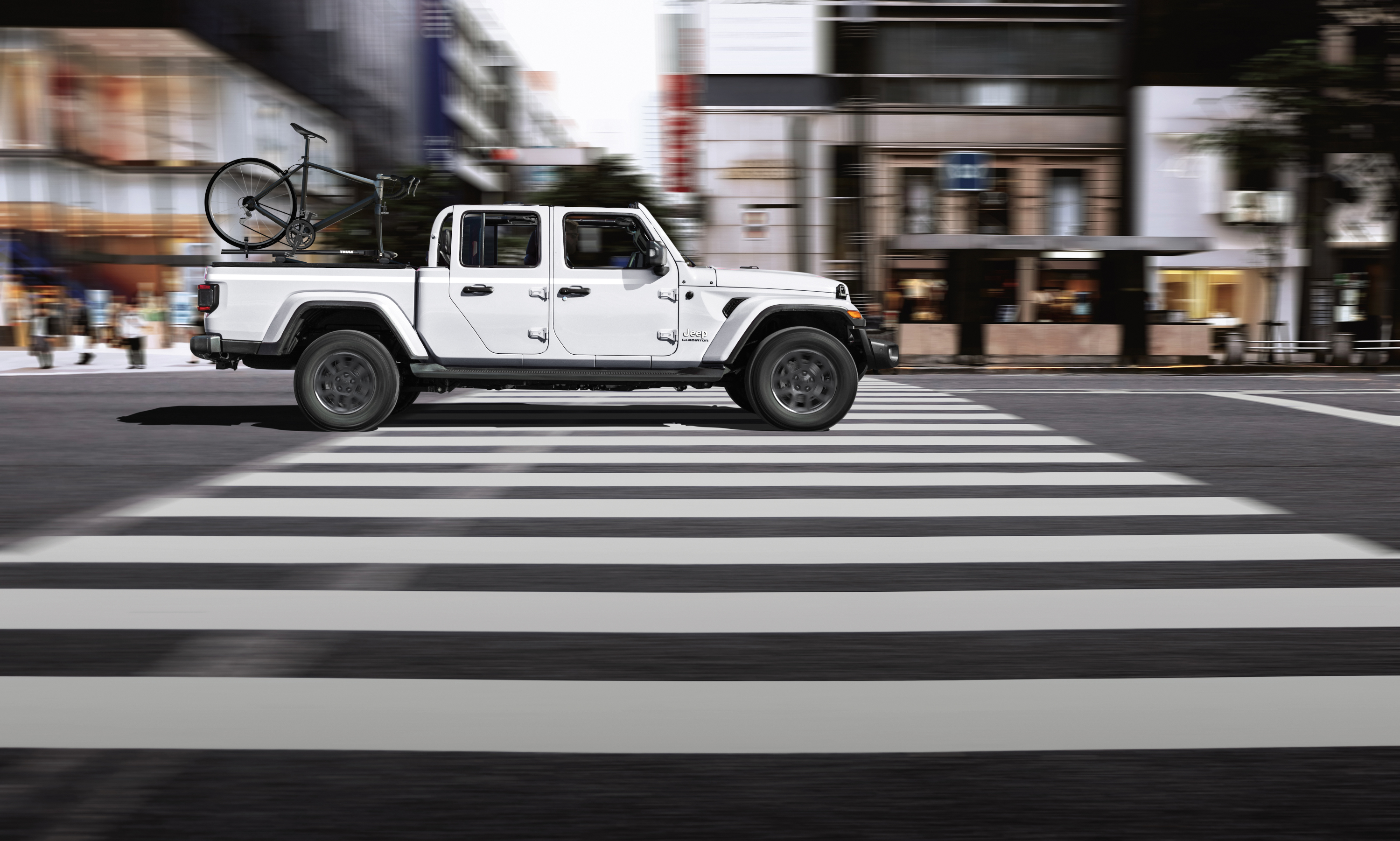 Jeep Gladiator 2022 : blanc vu de profil en ville avec vélo dans la benne