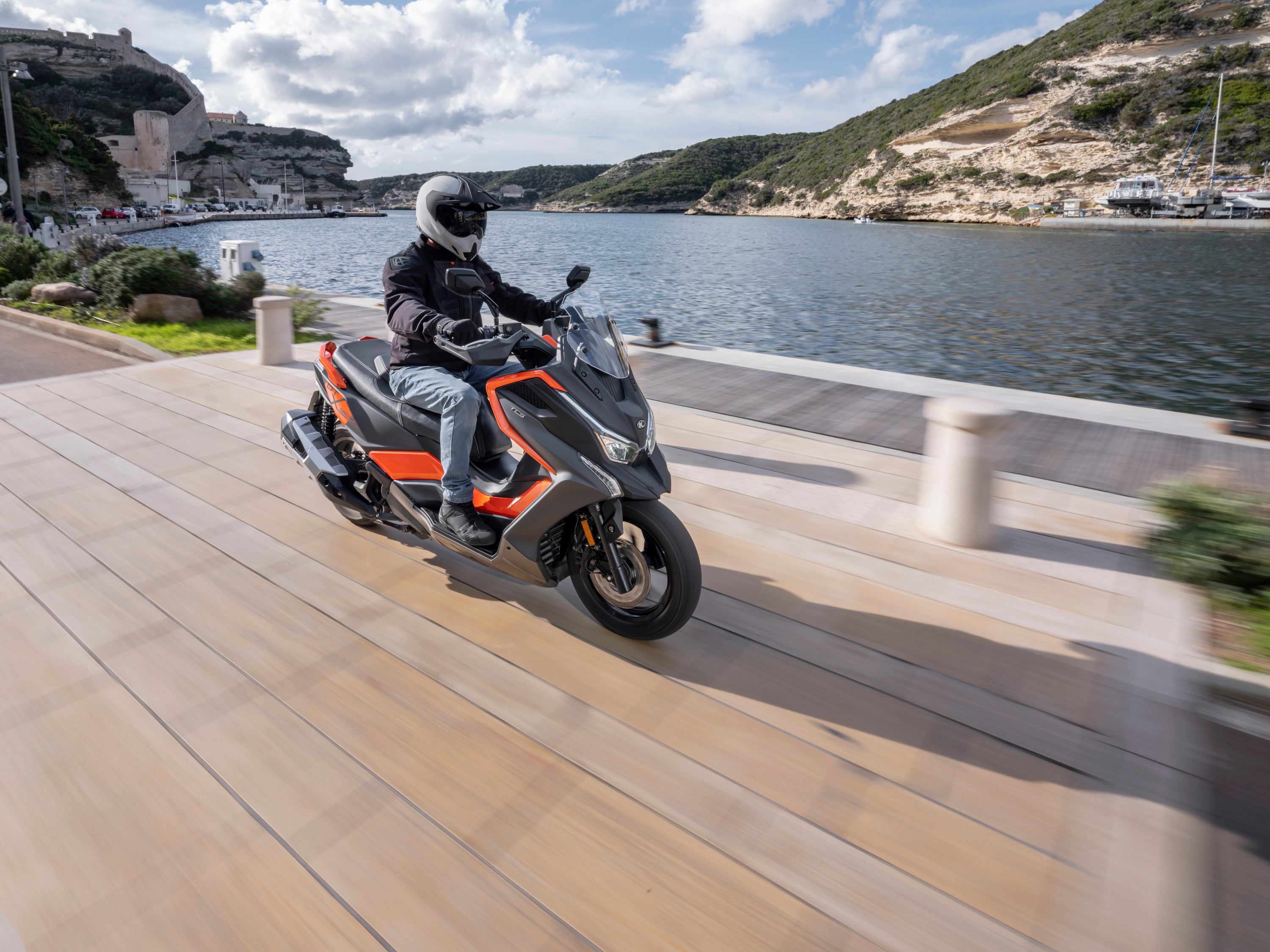 Kymco DTX 360 2024 : trois quarts avant droit sur route en bord de rivière