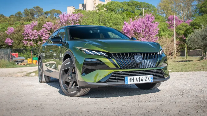 Peugeot 408 2026 : trois quarts avant droit statique en contre-plongée devant cerisiers en fleurs