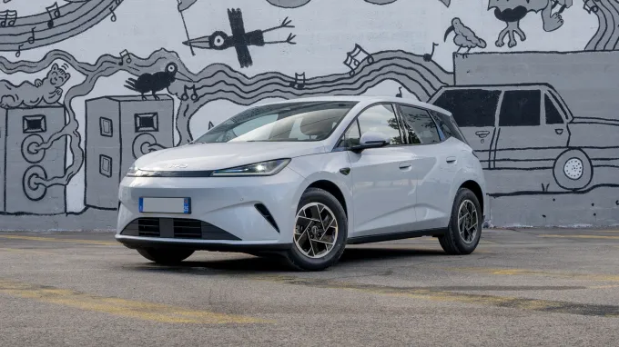 BYD Dolphin G DM-i 2026 grise : trois quarts avant gauche statique devant mur taggé